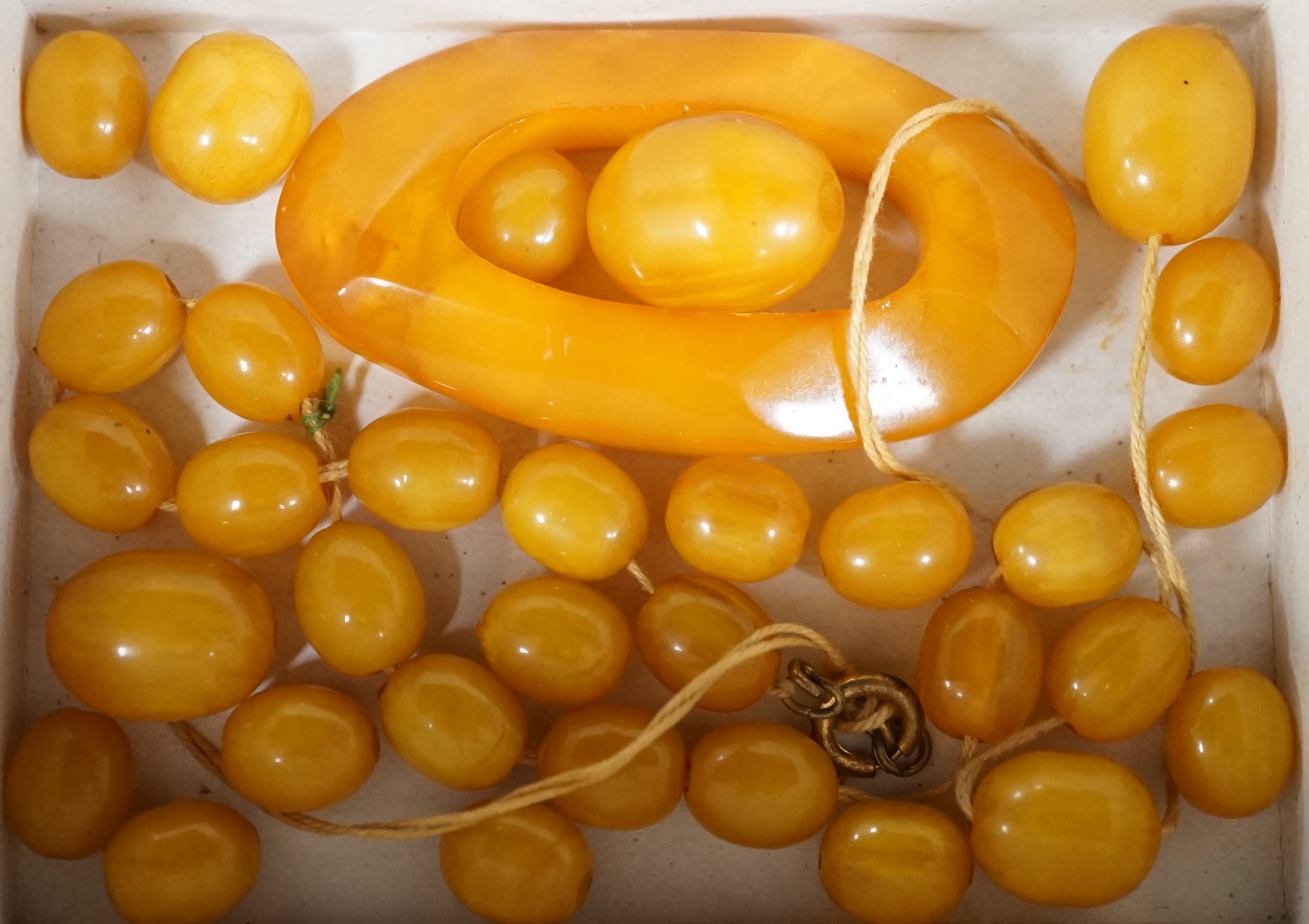 A small amber openwork pendant, 62mm, 12 grams and a group of simulated amber beads. Condition - poor to fair
